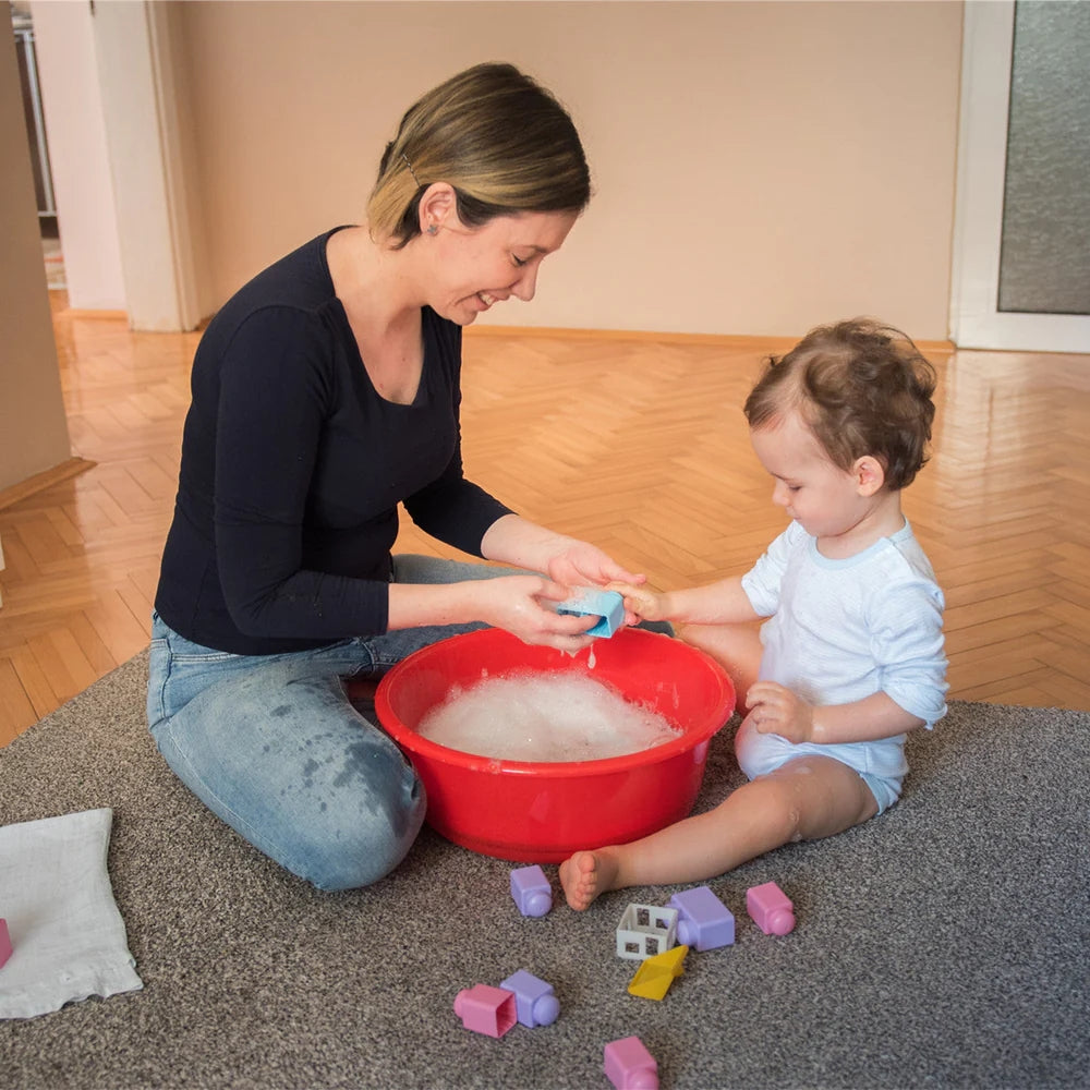 Mutter und Sohn waschen spielerisch zusammen Spielzeug im Wohnzimmer